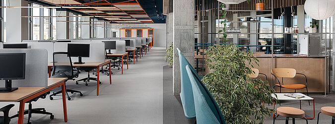 Modernes Büro mit Schreibtischen links und gemütlicher Loungeecke rechts im Bild