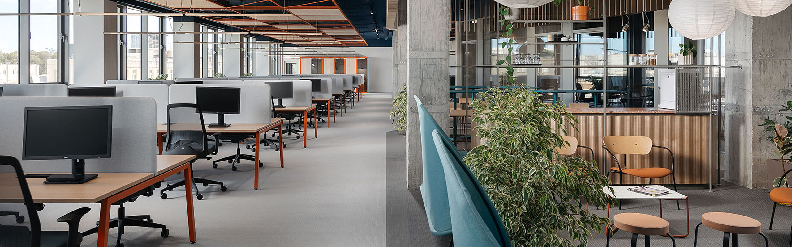 Modernes Büro mit Schreibtischen links und gemütlicher Loungeecke rechts im Bild