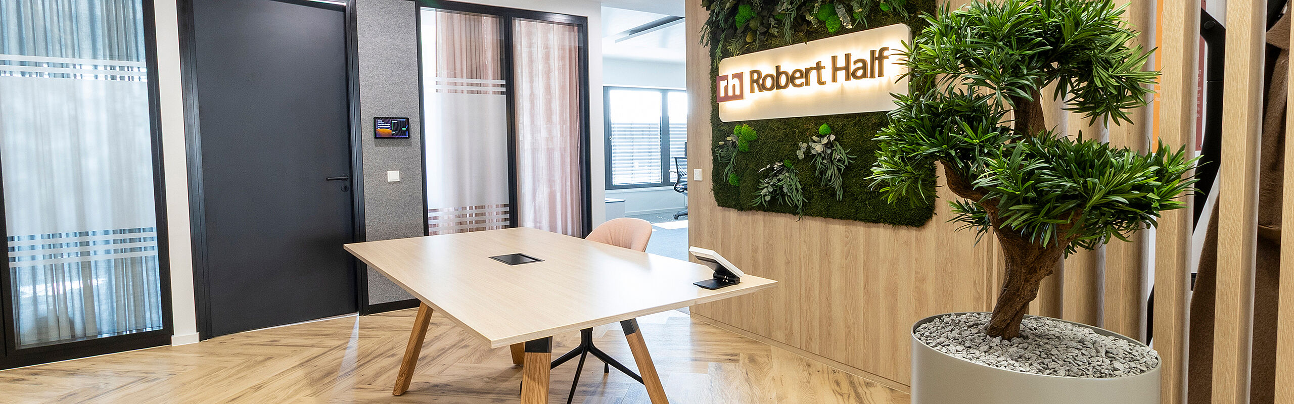 Reception area Robert Half with table and moss picture with logo Plant on the right in the picture Acoustic boxes on the left in the picture