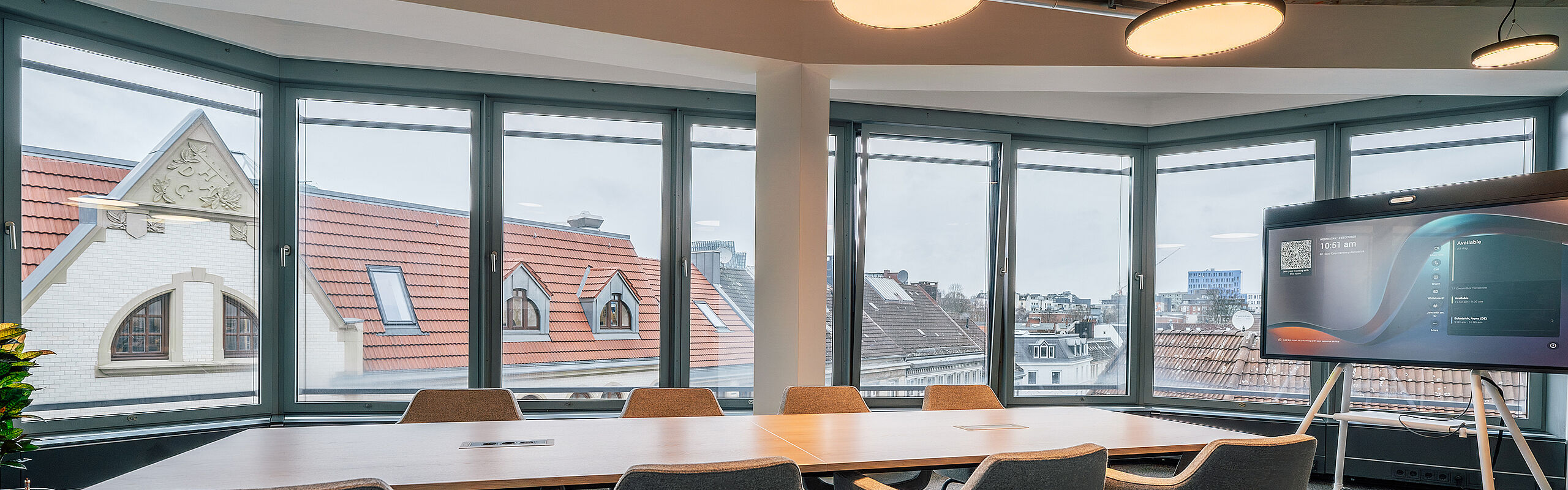 Moderner Besprechungsraum mit großem Tisch und umlaufender Fensterfront – Arbeitswelt für Austausch und Planung im Kontext ganzheitlicher Bürogestaltung.