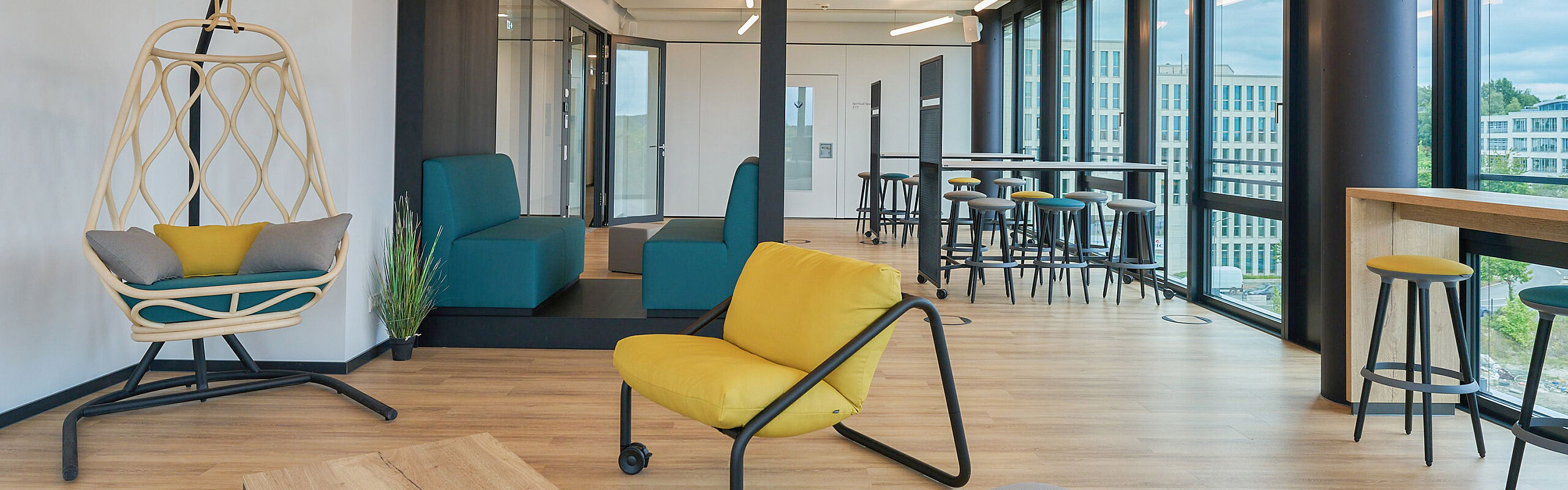 Modernes Büro mit Hängesessel, gelben Sessel, Hochtisch und Barhocker und Sitzbank