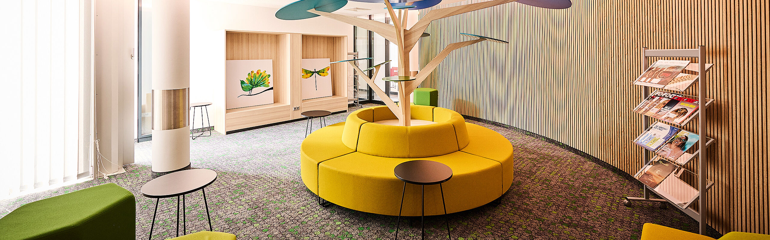 Collaboration area with colorful seat cushions and a minimalist decorative tree in the center of the room