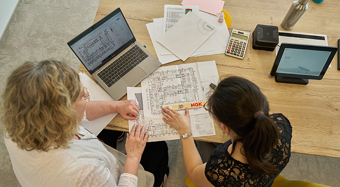 Team arbeitet gemeinsam an Plänen und Materialien – Detailabstimmung in der Ausführungsplanung von Büro- und Arbeitswelten.