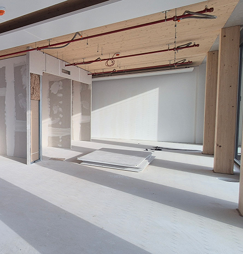 Shell construction phase of an office fit-out with partially installed drywall partitions, visible ceiling services and natural daylight. The space is currently undergoing interior fit-out and is being prepared for a modern workplace environment.