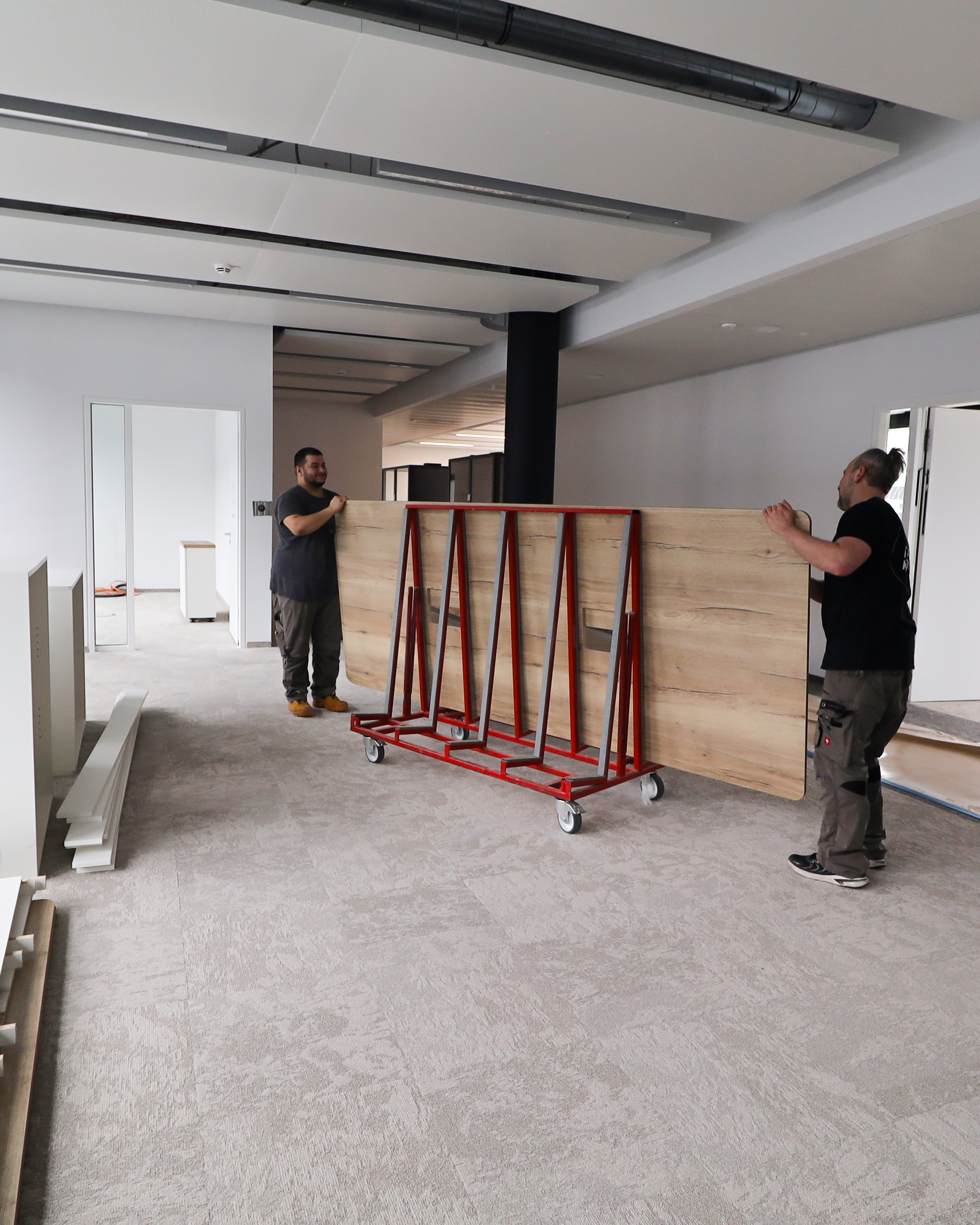 Büroausbau mit coneon - Jetzt anfragen! Innenausbau eines Büros zwei Menschen tragen eine Holzplatte