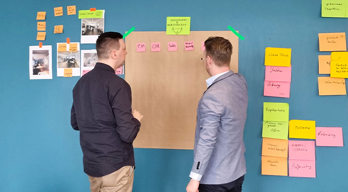 Zwei Menschen stehen vor einer Wand mit Post-its