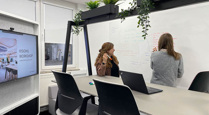 Zwei Personen schreiben an ein Whiteboard in einem modernen Büro 