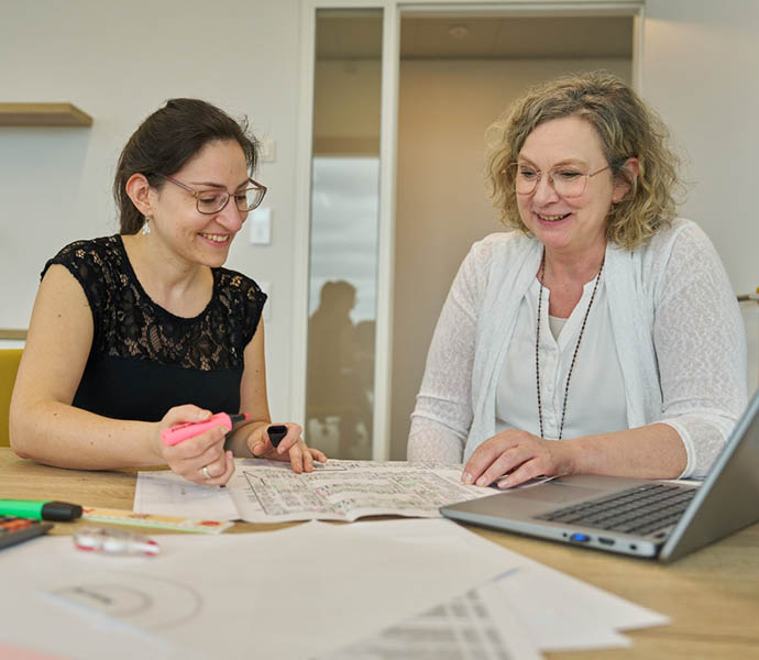 Zwei Personen schauen sich lachend einen Grundrissplan an