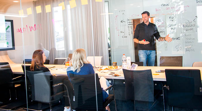 Eine Person präsentiert vor einer anderen Person im Meetingraum