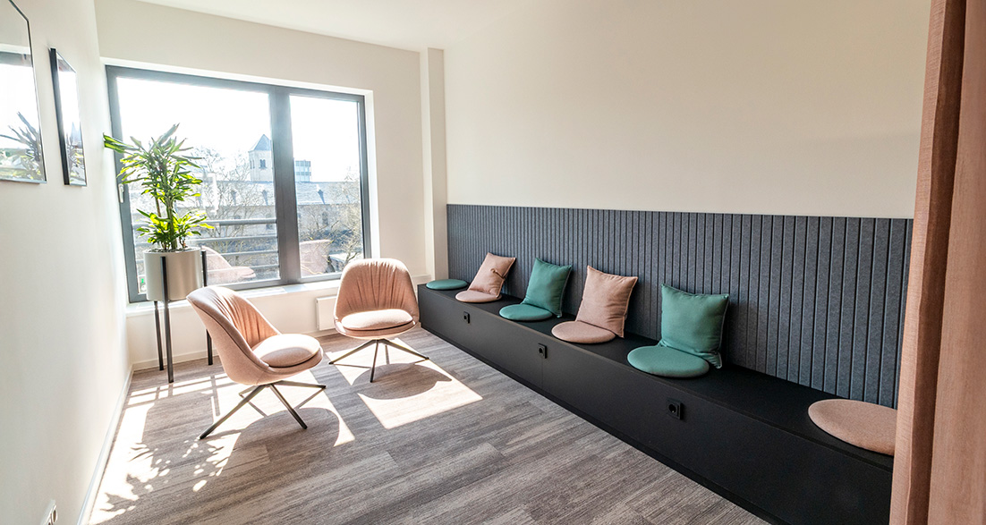 Rückzugsbereich mit Sitzbank und Kissen und rosanen Stühlen