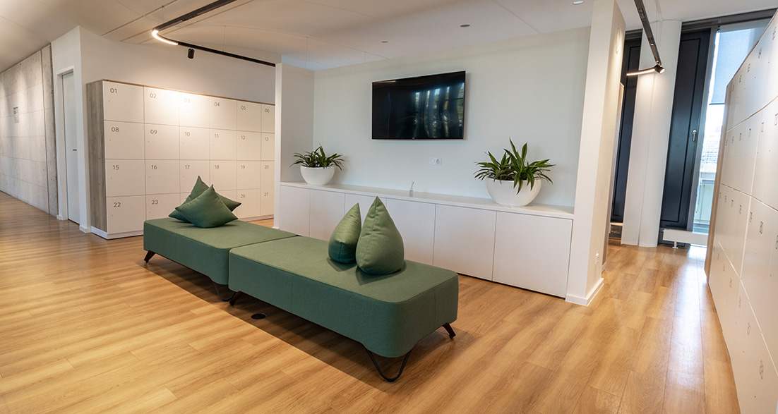 Bereich mit Schließfächern und Sitzmöglichkeit auf grünem Loungesofa
