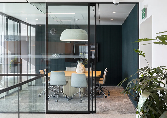 Modernes Büro mit Glaswänden um hellen Konferenzraum und Pflanze