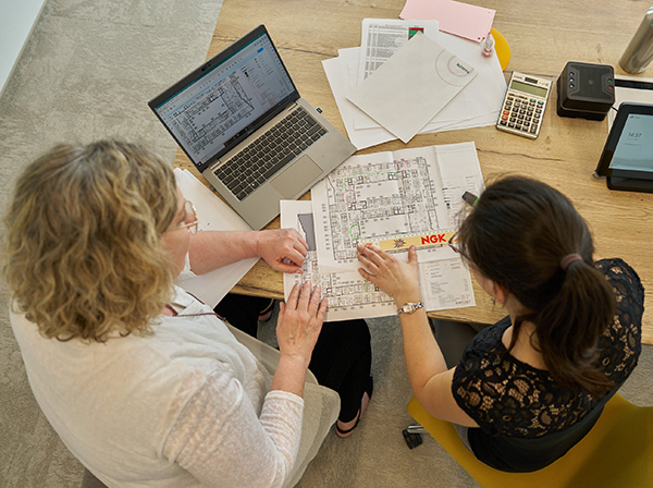 Zwei Personen sitzen über einer Planung eines Grundrisses