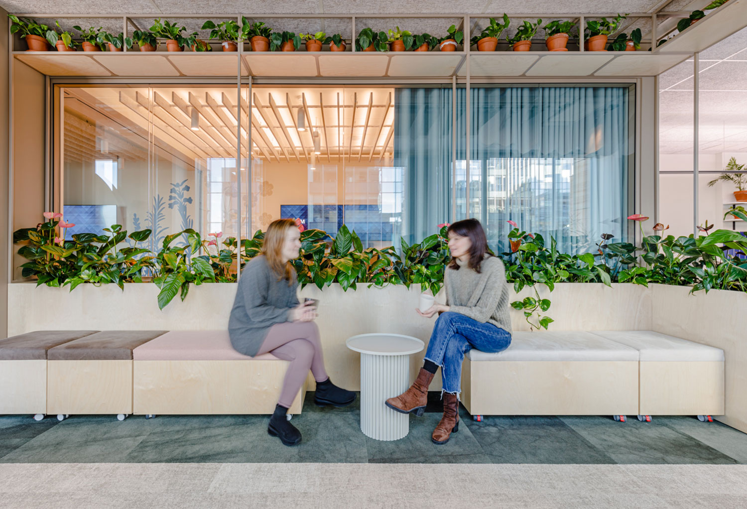 Zwei Mitarbeiterinnen unterhalten sich in Aufenthaltsraum auf modernen Sitzgelegenheiten