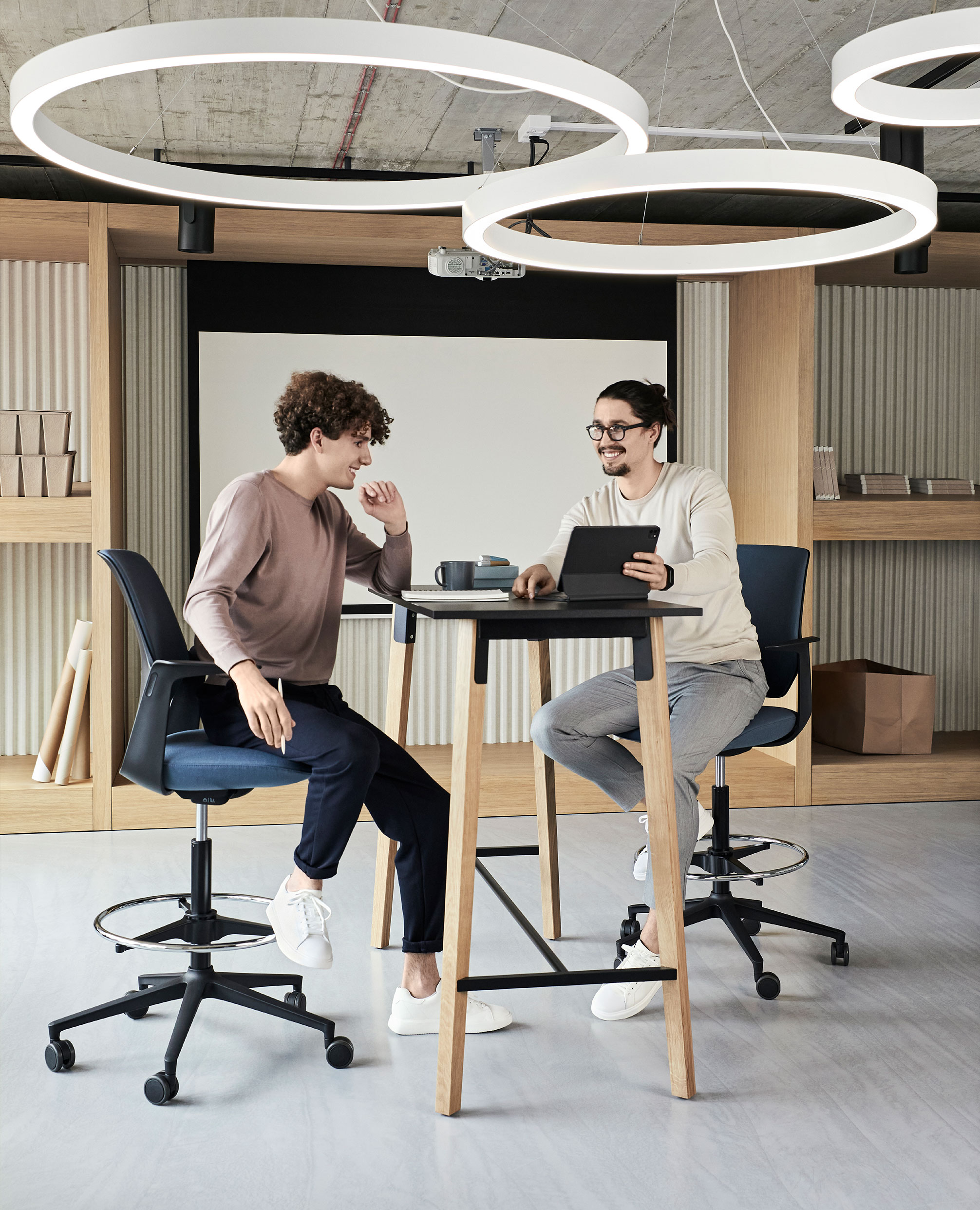 Zwei Personen haben eine Besprechung an einem Stehtisch in moderner, heller Atmosphäre 