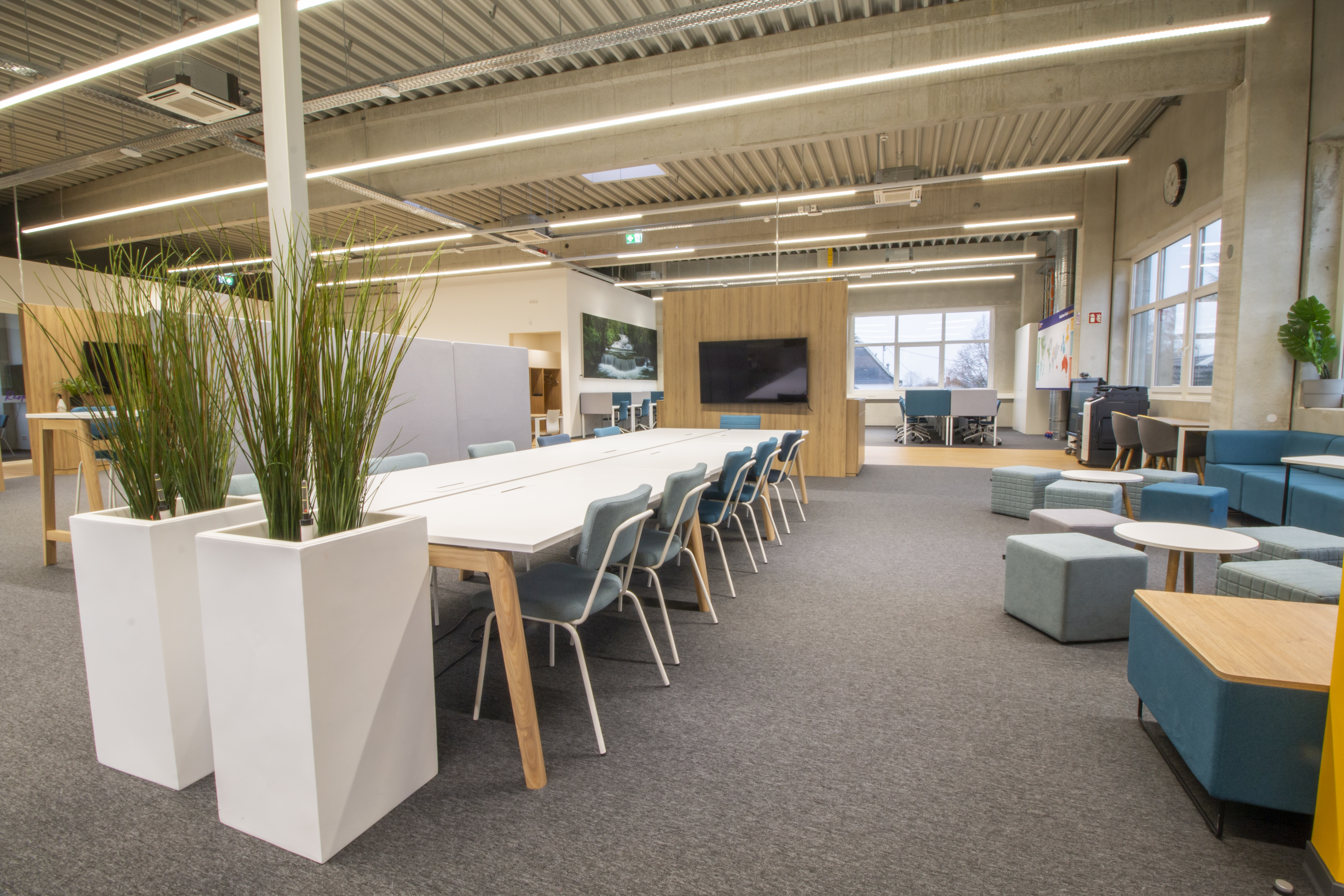 Langer Konferenztisch und kleine Arbeitsnischen mit Bänken.