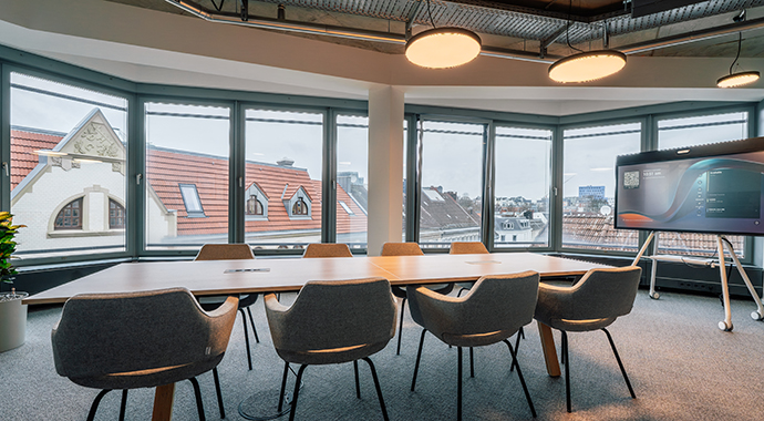 Modern conference room with large meeting table, presentation screen and panoramic windows overlooking the city