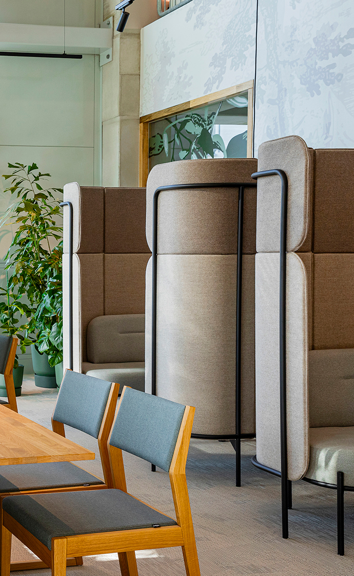 Acoustic seating niche with upholstered walls and wooden chair in a modern office space designed for focused work
