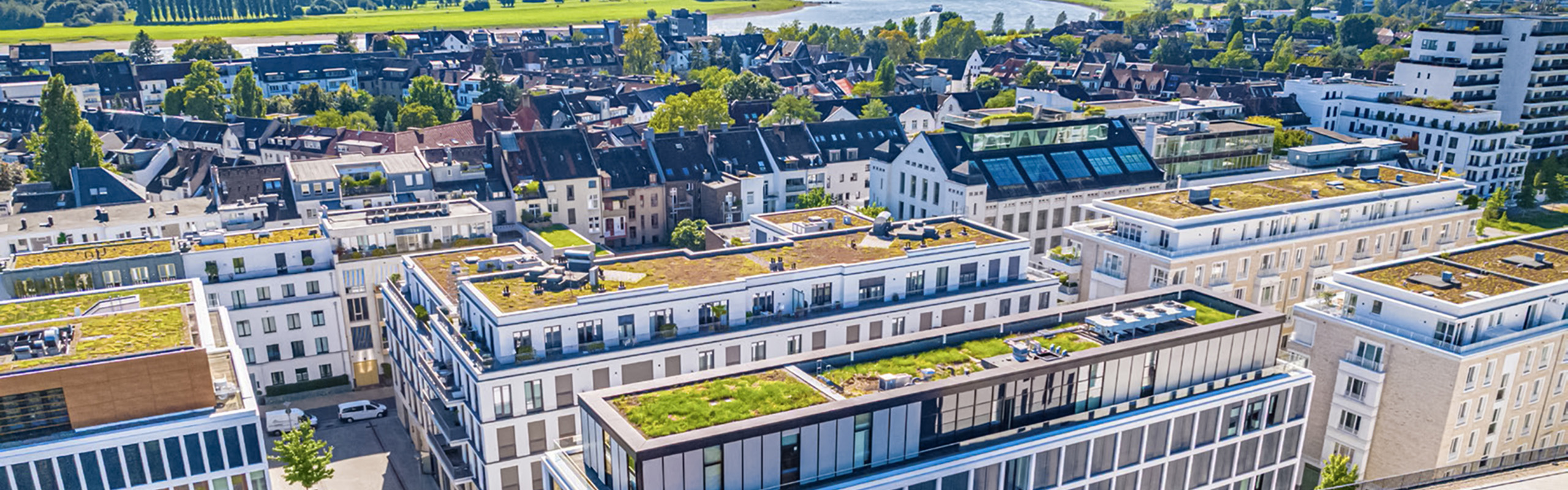 Bild aus der Vogelperspektive auf einen Stadtteil mit Hochhäusern und Fluss im Hintergrund