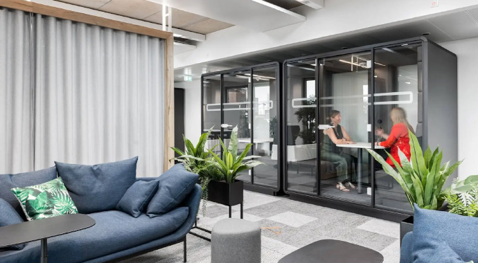 coneon: Die Bedeutung flexibler Bürokonzepte Zwei Personen sitzen in einer Akustikbox in einem offenen Büro