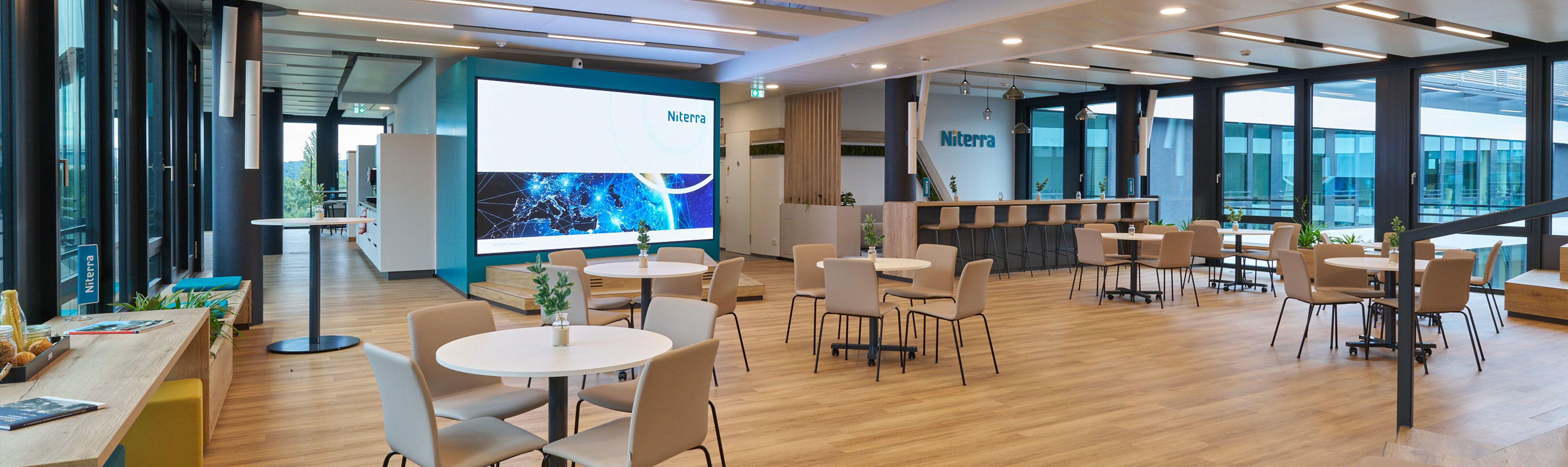 coneon: Praxisbeispiel New Work Bürokonzept Offener Gemeinschaftsraum mit großem Bildschirm