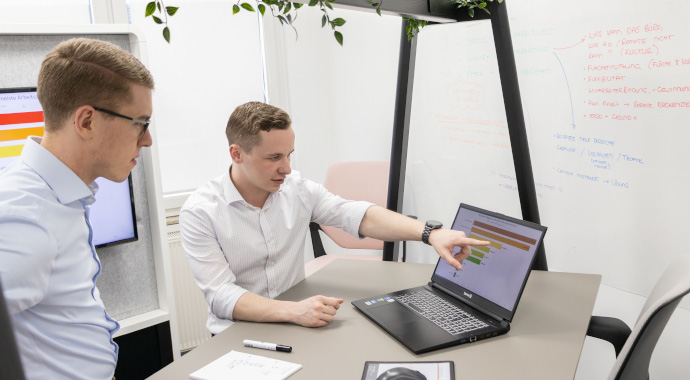 New Work Beratung von coneon Zwei Personen an einem Stehtisch mit Laptop und einer Grafik