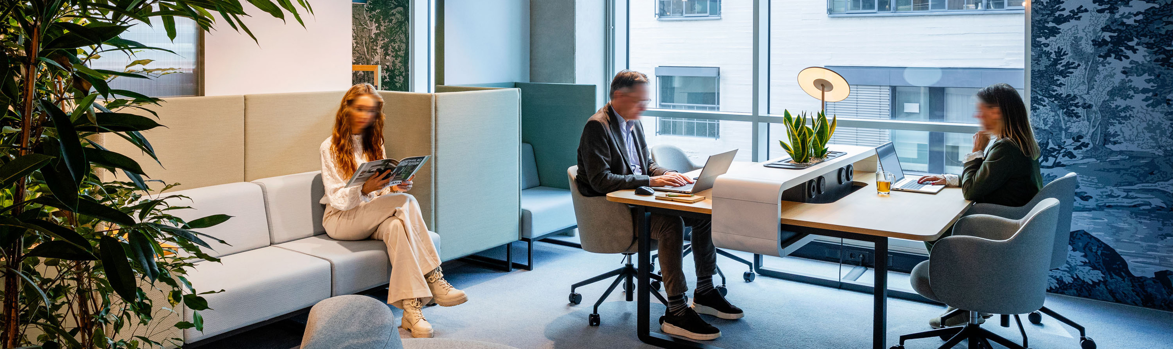 Drei Personen in agilem Büro mit großem Fenster