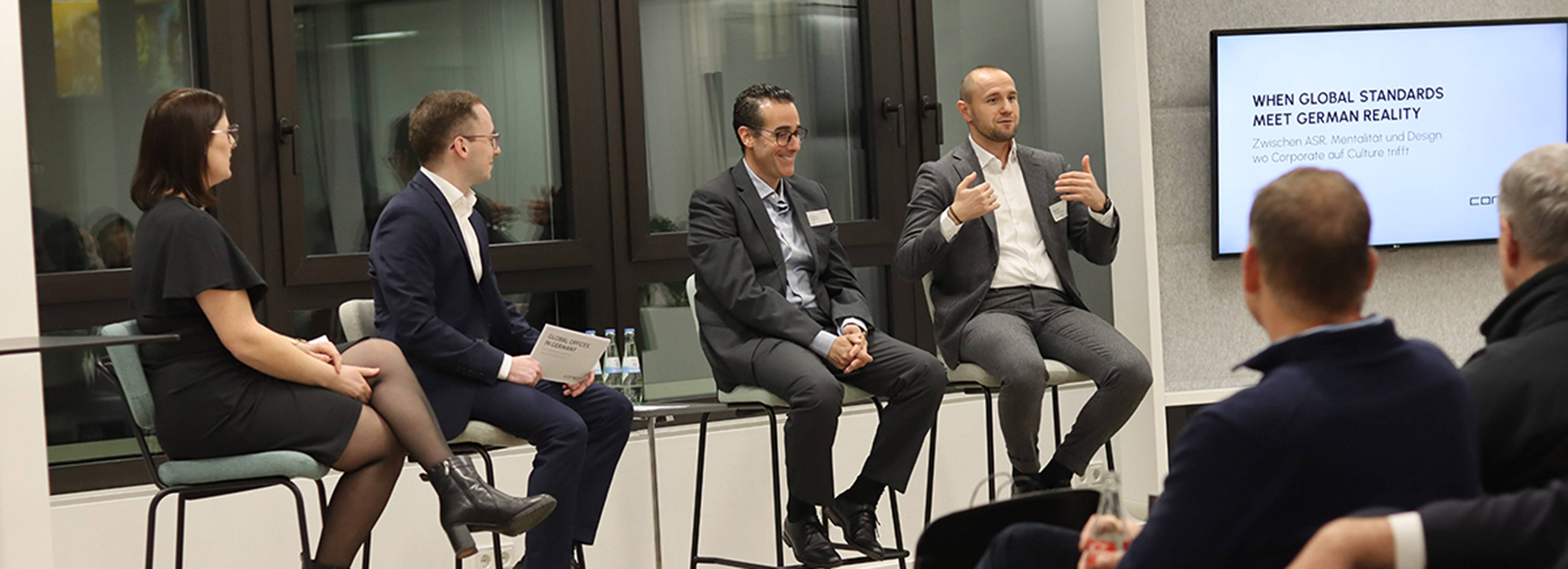 Four people on high chairs in the panel discussion