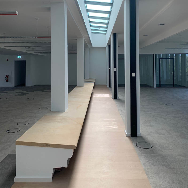 Bürofläche während der Realisierung mit zentraler Sitzbank, Stützen und noch unfertigem Boden