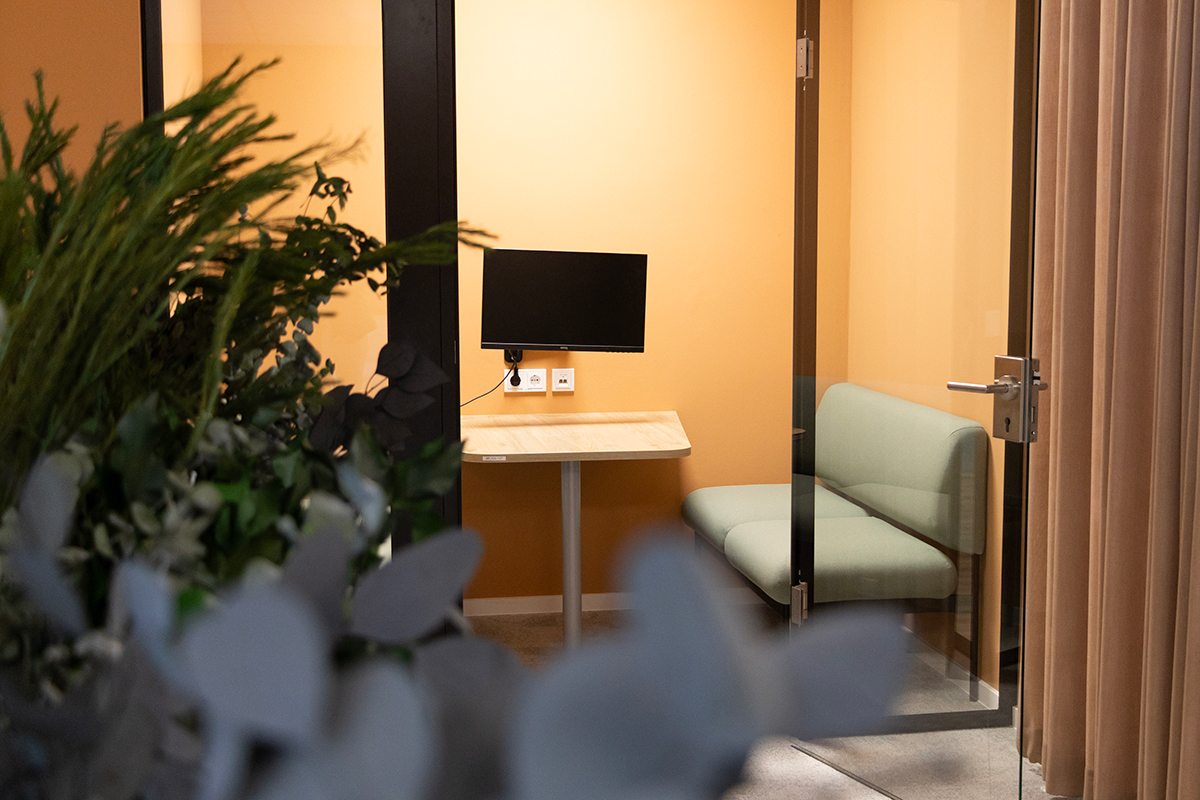 Small meeting room with desk, screen, and seating, designed as a quiet space for focused conversations and individual work.