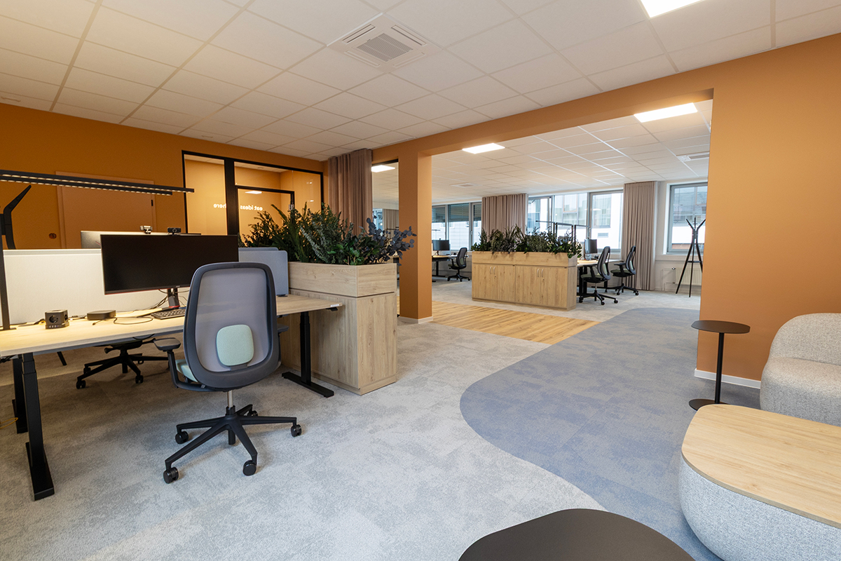 Open-plan office area with workstations, integrated greenery, and clearly defined zones supporting both collaboration and focused work.