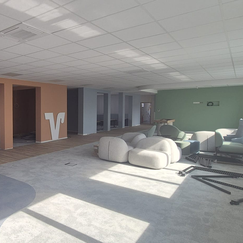 Office space nearing completion with installed lounge furniture, natural daylight, and final interior elements being prepared for handover.
