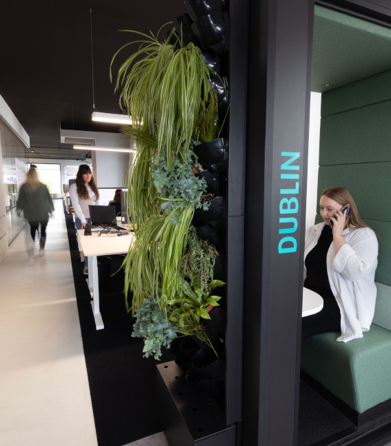 Aktivitätsbasiertes Arbeiten mit coneon Menschen im Büro, offene Telefonbox und ein langer gang mit Schreibtischen