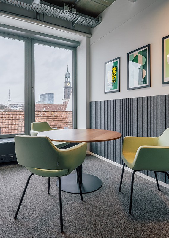 Kleiner Besprechungsplatz mit Holztisch und Stühlen am Fenster